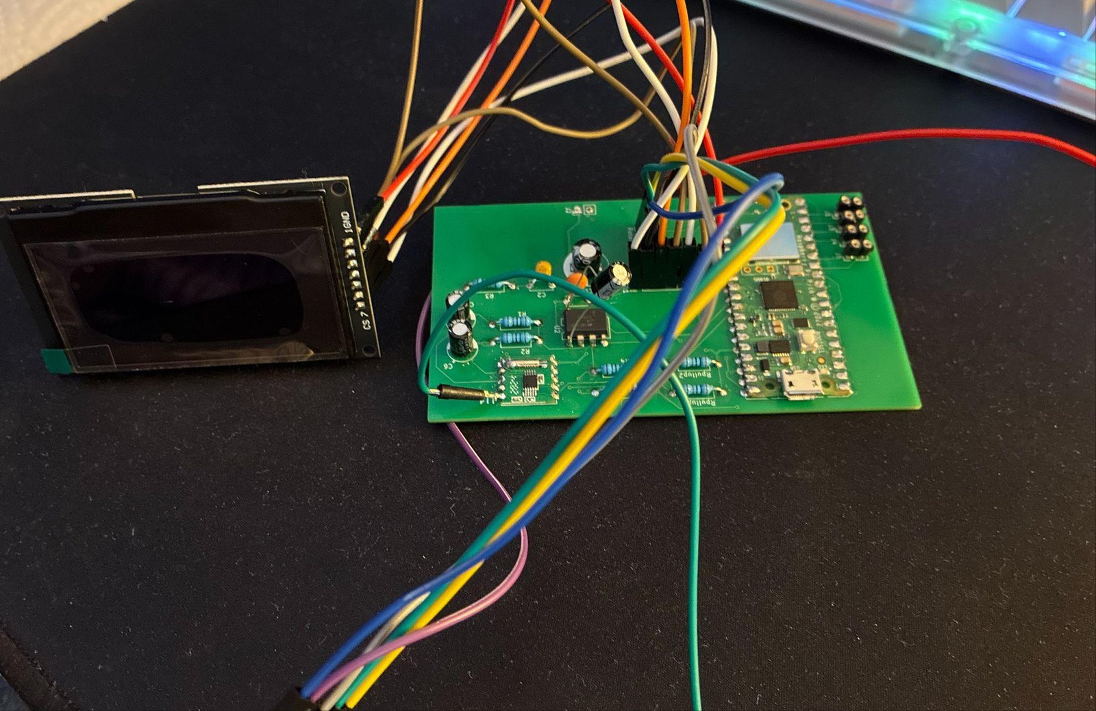 The assembled two-layer PCB with the Pico W, RDA5807M tuner, and LM386 amplifier populated, wired to the OLED module